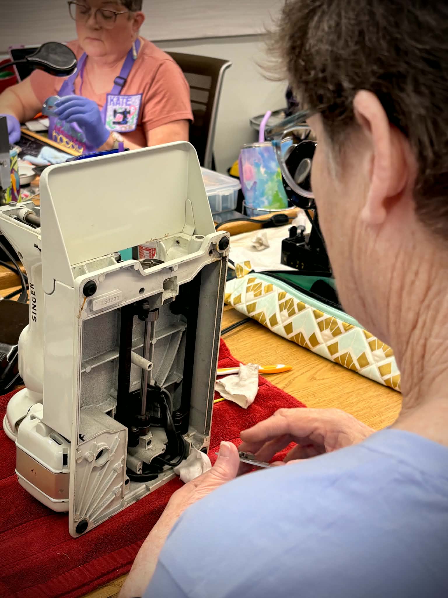 Student examining inside of Singer Featherweight at retreat